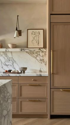 a kitchen with marble counter tops and wooden cabinets in the corner, along with artwork on the wall