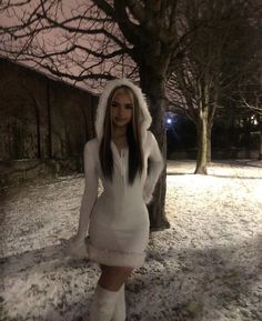 a woman in a white bunny costume posing for the camera with trees and snow around her