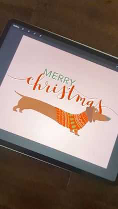 a tablet with a dachshund wearing a sweater and merry christmas written on the screen