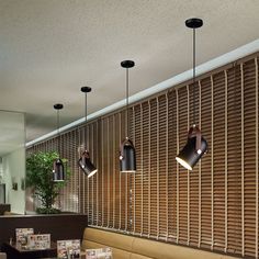 a restaurant with tables and chairs, lights hanging from the ceiling above them on wooden slats