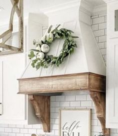 a kitchen with white cabinets and a wreath on the top of the hood above the stove