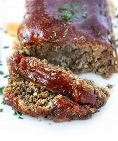 meatloaf with sauce and herbs on a white plate, ready to be eaten