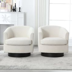 two white chairs sitting next to each other on a rug in front of a fireplace