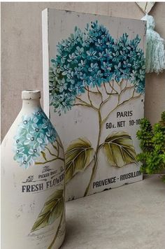 two painted vases sitting next to each other on a table with plants in the background