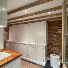 a kitchen with white cabinets and wooden counter tops next to a bathtub in the corner