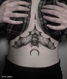 a woman's stomach with a bat tattoo on it