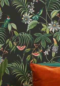 wallpaper with tropical leaves and flowers on a dark background, including an orange pillow