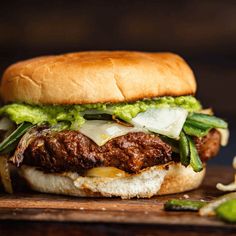 a sandwich with meat, onions and green beans on it sitting on a cutting board