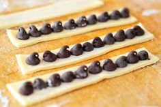 three pieces of chocolate chip cookie dough on a wooden surface