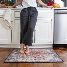 a woman standing on the kitchen floor with her hands in her pockets and feet up