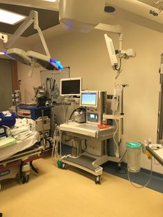 a hospital room with medical equipment and monitors on the wall, including an operating table