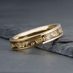 two yellow gold wedding bands with diamonds on them sitting on top of a stone slab