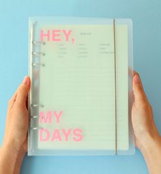 two hands holding a notebook with the words hey, my days written on it in pink