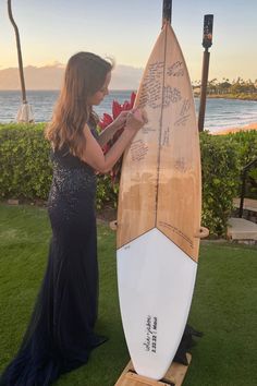 a woman standing next to a surfboard with writing on it