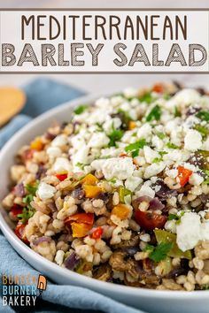 mediterranean barley salad in a white bowl with feta cheese and herbs on the side