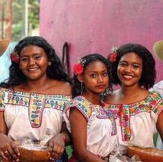 three women in traditional mexican dress are holding baskets and smiling at the camera while standing next to each other