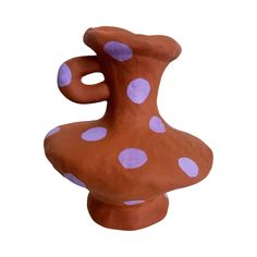 a brown and purple ceramic vase with polka dots on it's side, against a white background