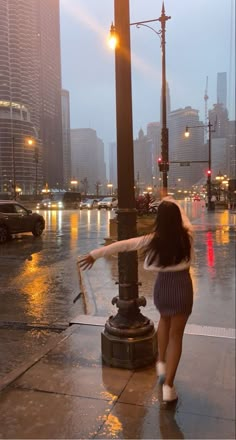 a woman is walking in the rain with her arms spread out and she is holding an umbrella