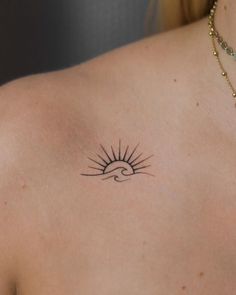 a woman's back with a tattoo on her shoulder and the sun in the sky