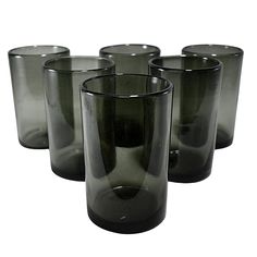 four black glass tumblers sitting next to each other