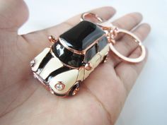 a hand holding a gold and black car shaped keychain