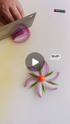 a person cutting onions with a knife on top of it and an onion flower in the middle