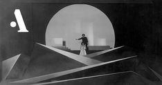 black and white photograph of a man standing in front of a large object with long lines on it