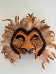 an animal mask with feathers on it's face is hanging up against a wall