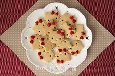 a white plate topped with cookies covered in frosting and red berries on top of a table