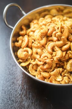 a metal bowl filled with cashews on top of a table