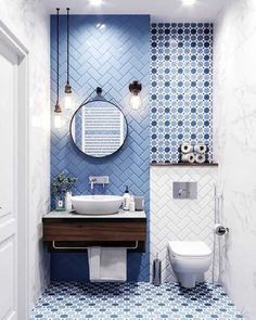 a bathroom with blue and white tiles on the walls, toilet, sink and mirror