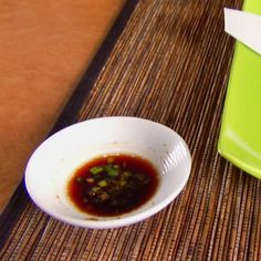 a white bowl filled with food next to a green container on top of a table