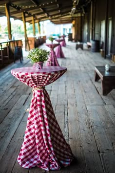 a row of tables covered in red and white checkered cloths sitting on top of a wooden floor