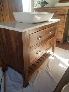 a bathroom sink sitting on top of a wooden counter next to a mirror and cabinet