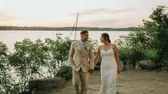 a bride and groom are walking by the water