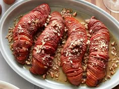 a white bowl filled with sliced up lobsters on top of a wooden table next to wine glasses