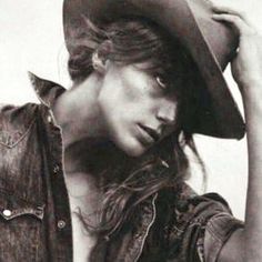 black and white photograph of a woman wearing a cowboy hat with her hands on her head