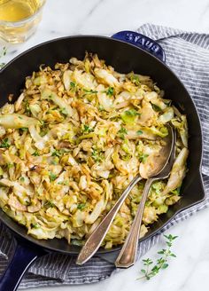 a skillet filled with cabbage and other vegetables on top of a white marble counter