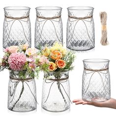 four glass vases with flowers in them and one being held by someone's hand