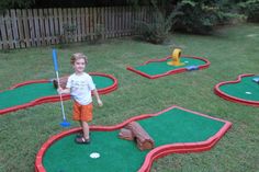 a little boy standing on top of a miniature golf course