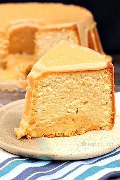 a slice of cake on a plate with the rest of the cake in the background