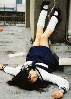 a woman laying on the ground with her feet up in the air next to a building