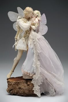 a figurine of a couple kissing on top of a piece of driftwood