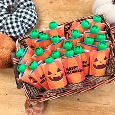 a basket filled with orange and green halloween candy bags sitting on top of a wooden table