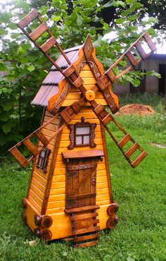 a small wooden windmill sitting in the grass