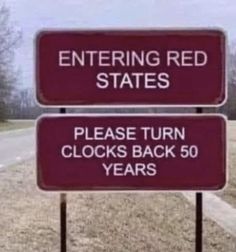 two red signs sitting on the side of a road next to a street sign that says entering red states please turn clocks back 50 years