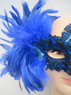 * Designed on a sturdy acrylic shiny half mask accented around the eyes with black liner and royal blue shiny embroidered flower and scrolled patterned lace in a custom design. * The right side is adorned with puffy plumes of fluffy and royal blue feathers. * To secure the mask there are two satin black ribbons on each side to be tied in the back. * A great piece for a Masked Ball, Class Reunion, Costume party or Play, Carnivale, Mardi Gras, Burlesque Occasion, Masquerade Ball, or Venetian Celeb Elegant Blue Eye Mask For Masquerade, Blue Venetian Mask For Carnival, Blue Venetian Masquerade Mask For Party, Blue Venetian Masks For Carnival, Blue Masquerade Mask For Mardi Gras Costume Party, Blue Masks And Prosthetics For Carnival Party, Blue Masquerade Mask For Mardi Gras Carnival, Blue Eye Mask For Carnival, Blue Party Eye Mask