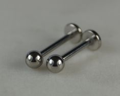 two metal balls are sitting on top of each other in front of a gray background