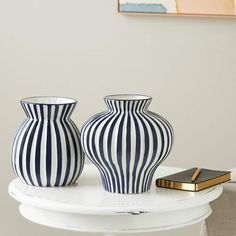 two blue and white vases sitting on top of a table next to a book