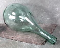 a green glass object sitting on top of a stone slab